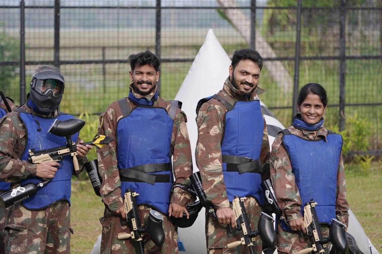 Colleagues smiling in paintball gear on a team outing
